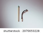 Small photo of Taranto, Italy - November 3, 2021: Two matches on a white background, one unused and one burned and curved, represents the concept of young and old age.