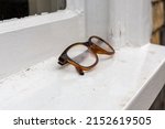 Pair of Tortoiseshell framed eye glasses folded and left on a white window ledge