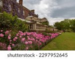 Small photo of Ticehurst, East Sussex, United Kingdom - May 5th 2019: The rear of Pashley Manor Gardens including a terrace with balustrade, covered with beautiful wisteria and extensive pink tulip borders