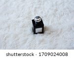 Small photo of Perfume bottle in dicey shape with white label and silver metallic cap on white background. Fluffy and clean background. Minimal concept.