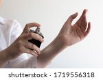 Small photo of Close up of female hands applying perfume on her wrist. Testing new fragrance on hand. Holding small dicey bottle and spraying.