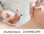 Cosmetologist performs the chin lift procedure by injecting beauty injections. Doctor injecting hyaluronic acid into the ching of a woman as a facial rejuvenation treatment.