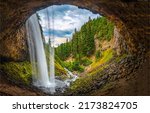 Waterfall over a cave in the forest. Waterfall at cave. Forest cave waterfall. Waterfall in forest