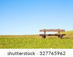 A calm place to rest and relax. An empty wooden bench  over a serene blue sky waiting for a hiker or casual walker to sit and rest.