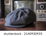 Small photo of Detail of a classic eight-panel newsboy hat in tweed fabric herringbone in midnight black on a classic electronic background