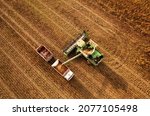 Small photo of Combine harvester working in wheat field. Harvesting machine during cutting crop in farmland. Combines grain harvesting. Harvester loads wheat in truck for transportation to a flour and bread plant