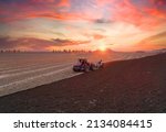 Small photo of Tractor Plowing field on sunset. Cultivated land and soil tillage. Tractor with disc cultivator on land cultivating. Agricultural tractor on cultivation field. Tractor disk harrow on plowing field.