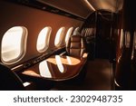 A first class area in a business jet with the sunset through a window