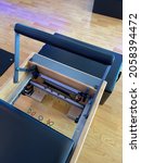 Small photo of A Pilates reformer bed with the springs unhooked.