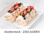 Small photo of Homemade meringue roll decorated with almond flakes, blueberries and strawberries in the white gift box on the white background. Meringue roulade with whipped cream on top.