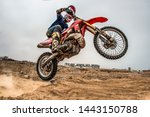 Shot of the professional motocross rider on his motorcycle on the extreme terrain track. Biker flying on a motocross motorcycle. Construction background and sky.