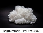 Small photo of Synthetic fiber, polyester fiber, siliconized holofiber, white sintepon on a black background. It is used as a filler for blankets, pillows, clothes and upholstered furniture.