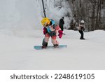 Small photo of Logoisk. Belarus. 01.06.2023. A teenage snowboarder descends the slope of a snow-covered mountain in special equipment. Snowboarding - descent at high speed on a special projectile - a snowboard.