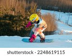 Small photo of Logoisk. Belarus. 01.04.2023. A teenage snowboarder descends the slope of a snow-covered mountain in special equipment. Snowboarding - descent at high speed on a special projectile - a snowboard.
