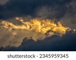 Small photo of A dramatic photo of a cloudy sky with the sun shining through the clouds. The clouds are dark and foreboding, but the sun's rays create a sense of hope and optimism.