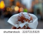 Small photo of Hand hold oliebol with paper napkins served with icing sugar powder, Traditional Dutch food or sweet known as doughnuts or dutchies, Oliebollen are traditionally eaten on New Year's Eve, Netherlands.