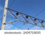 Small photo of Electric train trolley pole electrification system on railroad tracks with blue sky above