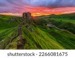 Small photo of Evening mood with sunset on the Isle of Skye. Countryside in Scotland in summer. Sun star on the horizon next to Castle Ewen rock. Colorful clouds in the sky. Green meadows and hills