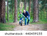 Little kid boy of 4 years and his grand father in summer forest with a bicycle. Grandpa teaching his boy. Man happy about success. Child with helmet. Safety, sports, leisure with kids concept.
