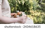 Small photo of Easter eggs and spring flowers in wooden bowl in female hands. Easter eggs in natural color. Easter in rustic stile