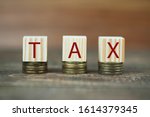 Small photo of wooden cubes on coins, the inscription taxes, the concept of tax encumbrance