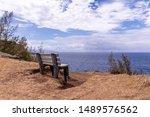 Small photo of An empty bench on the edge of a cliff overlooking ocean, Ohai trail, Maui, Hawaii