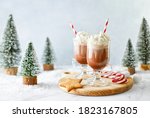 Small photo of Hot chocolate or coffee with whipped cream served with a candy cane, marshmallows, and gingerbread star, front view, winter holidays treats concept