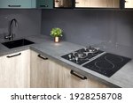 Upscale modern flat design Aqua Menthe kitchen in luxury home with induction electric hob flat oak or walnut wooden panels with flower in vase and sink with tap mixer of modern design.