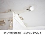 Small photo of Swelling leaking of whitewash and plaster on ceiling of dwelling due to penetration of water from the top floor or roof, selective focus.