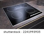 Grey countertop with black glossy built in ceramic glass induction or electric hob stove cooker with four burners in dark empty modern contemporary flat design loft kitchen interior.