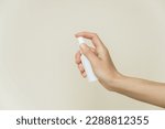 female hand holds a white spray bottle on a gray background. liquid products in spray bottles