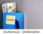 Small photo of Cash money dollars, pen, blue book on grey background, with sticky note ROYALTIES, concept of passive income from patent or copyright, side income or side hustle from intellectual property royalties