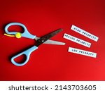 Small photo of Scissors with text paper HIGH, MEDIUM, LOW PRIORITY, concept of time management, arranges items or activities in order of importance or urgency