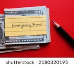 Small photo of On red background, cash dollar money with handwritten note EMERGENCY FUND, concept of financial goal to save rainy day money, budget set aside for unexpected expenses or safety net for future mishaps