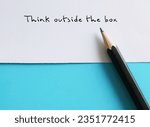 Small photo of Paper on blue background with text written by pencil THINK OUTSIDE THE BOX , concept of breaking status quo to find innovative solution or create something differently, stand out from the crowd