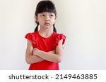 Small photo of Thai Asian kid girl, age 4 to 6 years old, cute face, long hair. wearing a red shirt She stood with her arms crossed. glanced upwards With a sad face, a frown, a bad mood, isolated white background