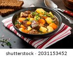 Traditional Irish stew in a black bowl on a dark background. Stew of lamb, potatoes, onions, carrots, and thyme. Traditional dish of St. Patrick