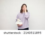 Small photo of Loving beautiful mother with diapers, teddy and a baby bottle in one hand makes tired expression. Concept: Mom is tired and motherhood. White background. Space for text. Mom chores.