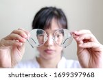 Short-sighted woman is holding glasses in hand with white background. symbolic photo for bad vision and refractive error