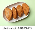 Small photo of deep fried curry puff,curry puff pastry, karipap,epok epok, spiral curry puff isolated a green pastel backdrop . thai curry puff concept.this pastry is asian traditional snacks