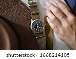 Vintage military wristwatch with nato leather strap and brown straw hat. Classic timepiece mechanical watch, Men fashion and accessories.