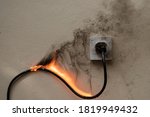 Small photo of On fire electric wire plug Receptacle on the concrete wall exposed concrete background with copy space