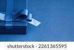 Small photo of Luxury gift box with a blue bow on blue. High angle view monochrome close up. Fathers day or Valentines day gift for him. Corporate gift concept or birthday party. Festive sale