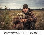 Man hunter with hunting dog Weimaraner friend portrait in rural field during hunting season