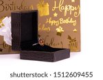 Small photo of Cinnamon stone ring in lather gift box and carry bag on white background. Happy birthday concept