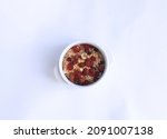 Small photo of A healthy breakfast is herculean porridge with the addition of nuts and dried fruits in a white bowl, isolated on a white background. Side view. Healthy food, carbohydrates. Top view.