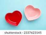 Red and pink heart shaped bowls on blue background. Top view