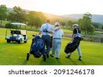 Small photo of Group of Asian people businessman and senior CEO enjoy outdoor sport golfing together at country club. Healthy men golfer holding golf bag walking on fairway with talking together at summer sunset