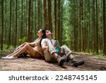 Happy Asian family couple travel on summer holiday vacation trip. Man and woman traveler enjoy outdoor active lifestyle hiking and resting together in pine tree forest mountain.