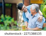 Small photo of Asian man surprise hugging elderly father from back at outdoor garden cafe restaurant on summer vacation. Family relationship, holiday celebrating, father's day and old people health care concept